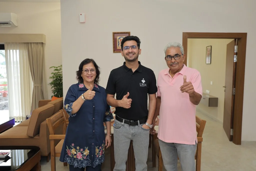 Happy senior parents with CHL Urja caregiver staff in modern apartment living room